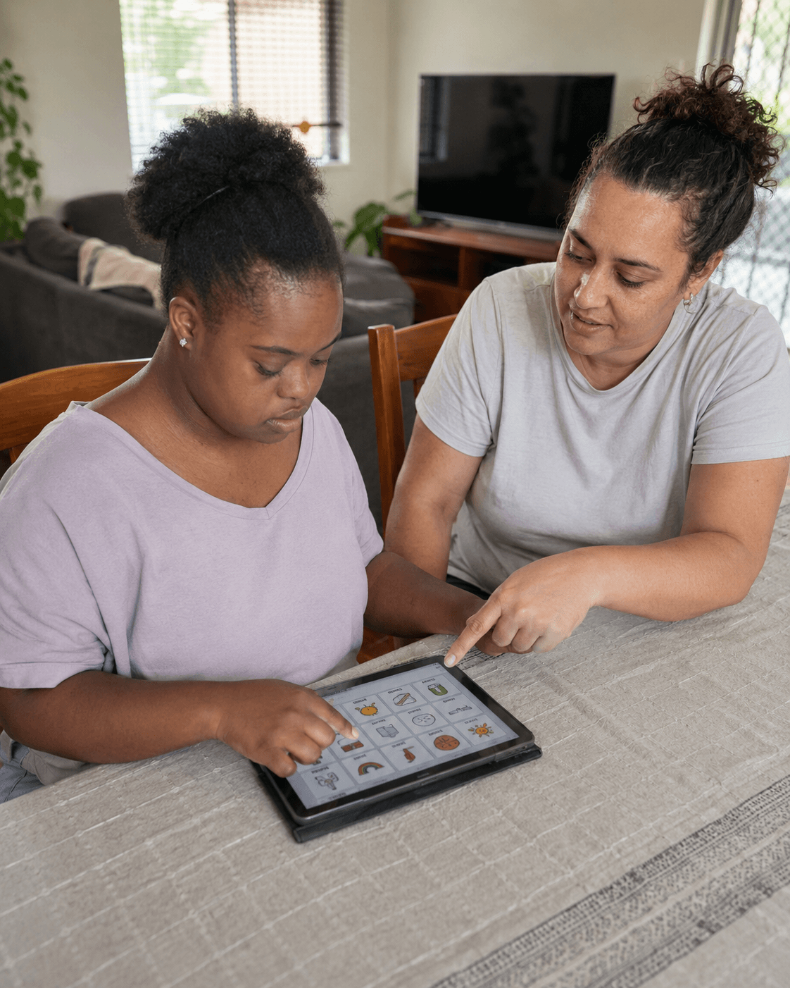 A support worker and young adult reviewing a tablet together at a table